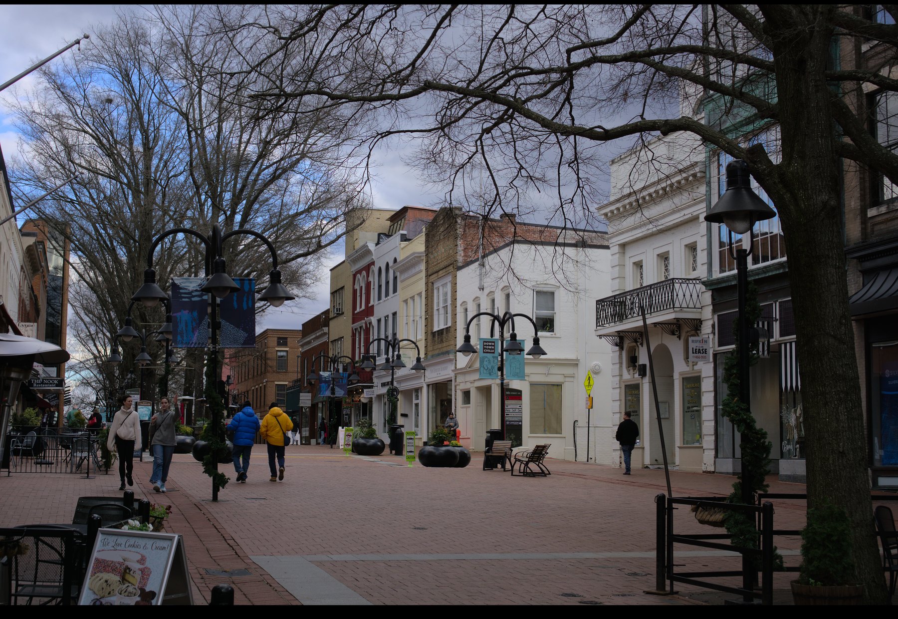 People walking along the brick-paved Charlottesville Downtown Mall on a winter day.